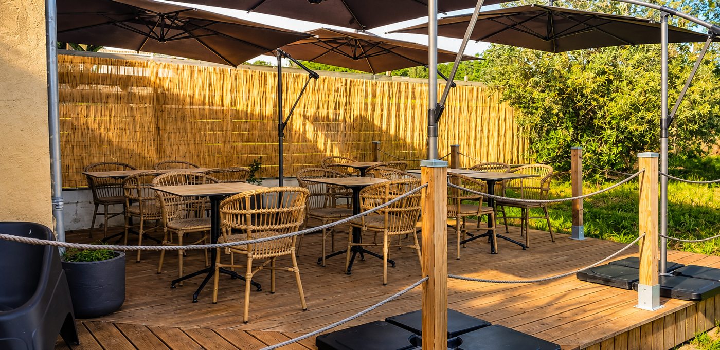 La terrasse arrière ombragée, abritée par une palissade, tables et fauteuils